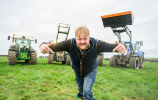 Kaleb Cooper in front of three tractors