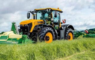 Tractor cutting grass in a field using mowing equipment, with freshly cut rows visible behind.