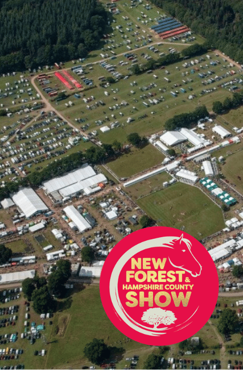 RABI-New-forest-hampshire-county-show-volunteer-2026 Aerial view of a large agricultural show with tents, vehicles and crowds spread across a showground, surrounded by woodland. An overlaid logo reads “New Forest & Hampshire County Show.”