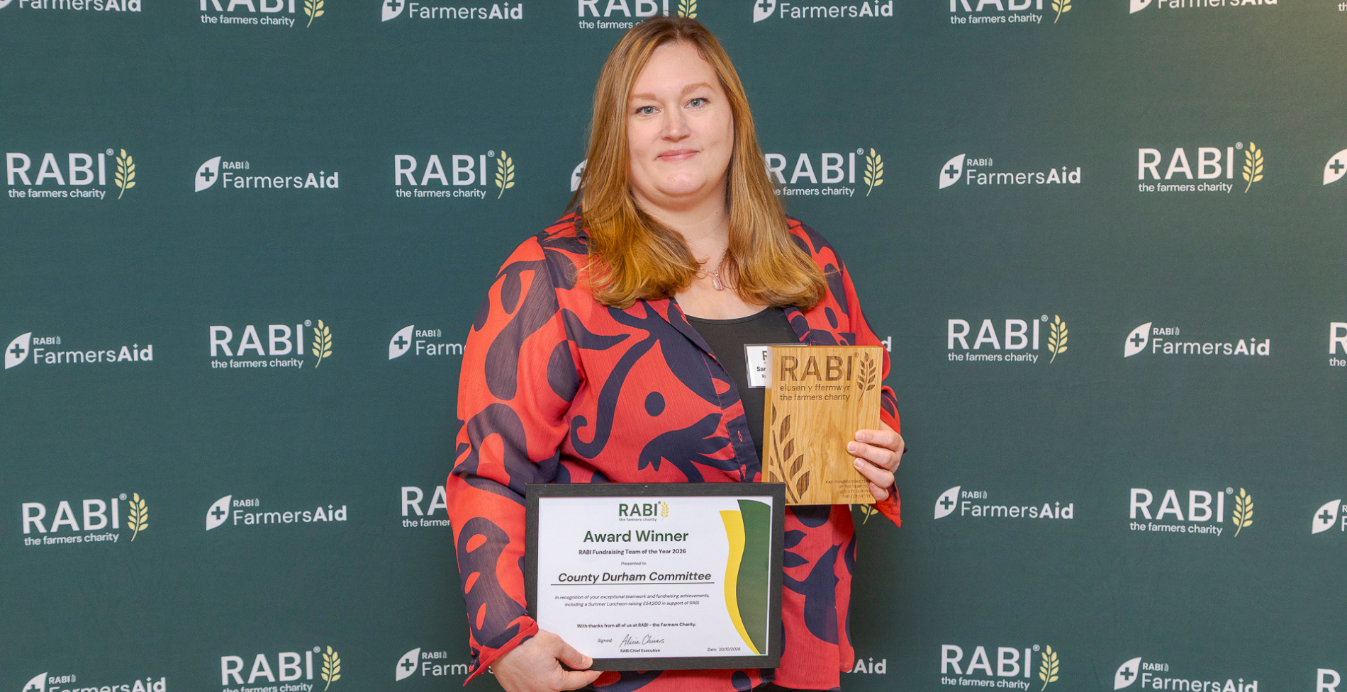 Representative of the County Durham Committee holding the RABI Fundraising Team of the Year 2026 trophy and certificate, in front of RABI and FarmersAid branding.